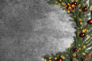 Photo of Christmas greeting card with space for text. Flat lay composition of fir tree branches and festive decor on grey stone background