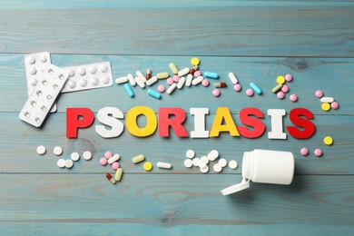 Photo of Word Psoriasis made of paper letters and pills on light blue wooden table, flat lay