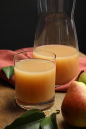 Fresh pear juice in glass and fruit on wooden table, closeup