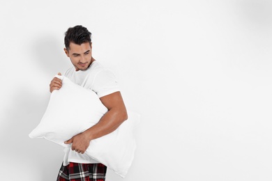 Young man with soft pillow on white background