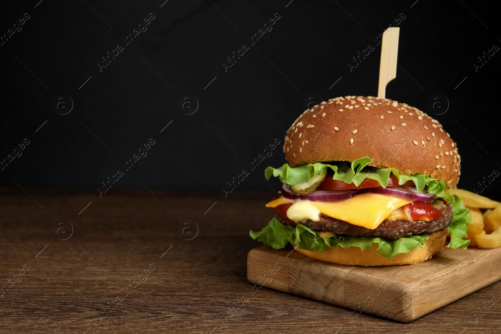 Photo of Delicious burger with beef patty and french fries on wooden table, space for text