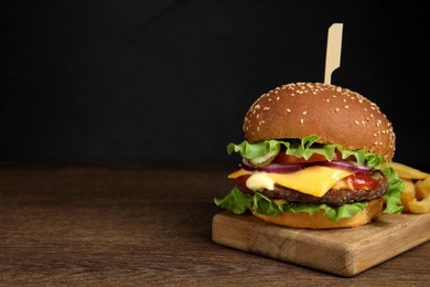 Delicious burger with beef patty and french fries on wooden table, space for text