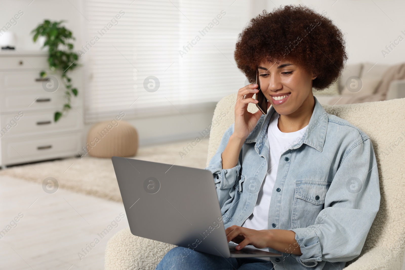 Photo of Young woman using laptop and talking on smartphone in room, space for text