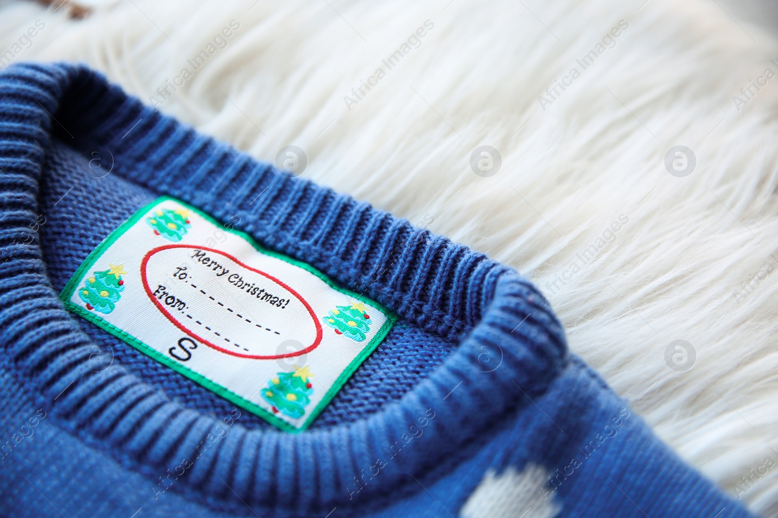 Photo of Christmas sweater with tag on fur, closeup