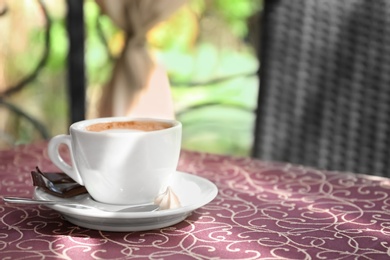 Cup of delicious aromatic coffee on table