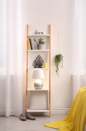 Stylish room interior with wooden ladder near white wall