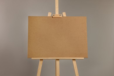 Wooden easel with blank board on grey background