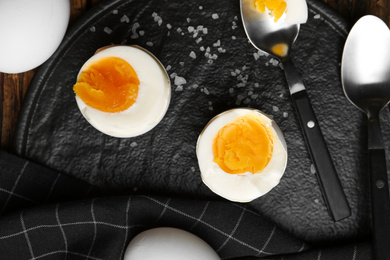 Photo of Tasty boiled chicken eggs on black slate plate, flat lay