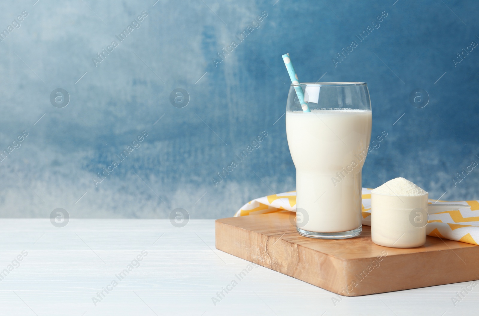 Photo of Protein shake in glass and powder on table. Space for text