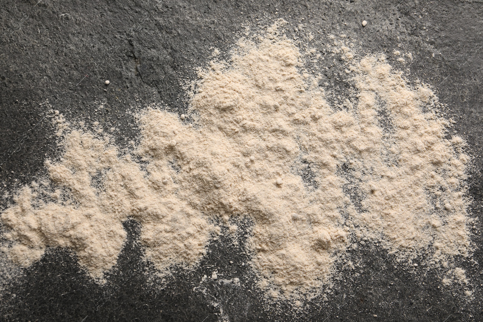 Photo of Scattered flour on grey textured table, top view