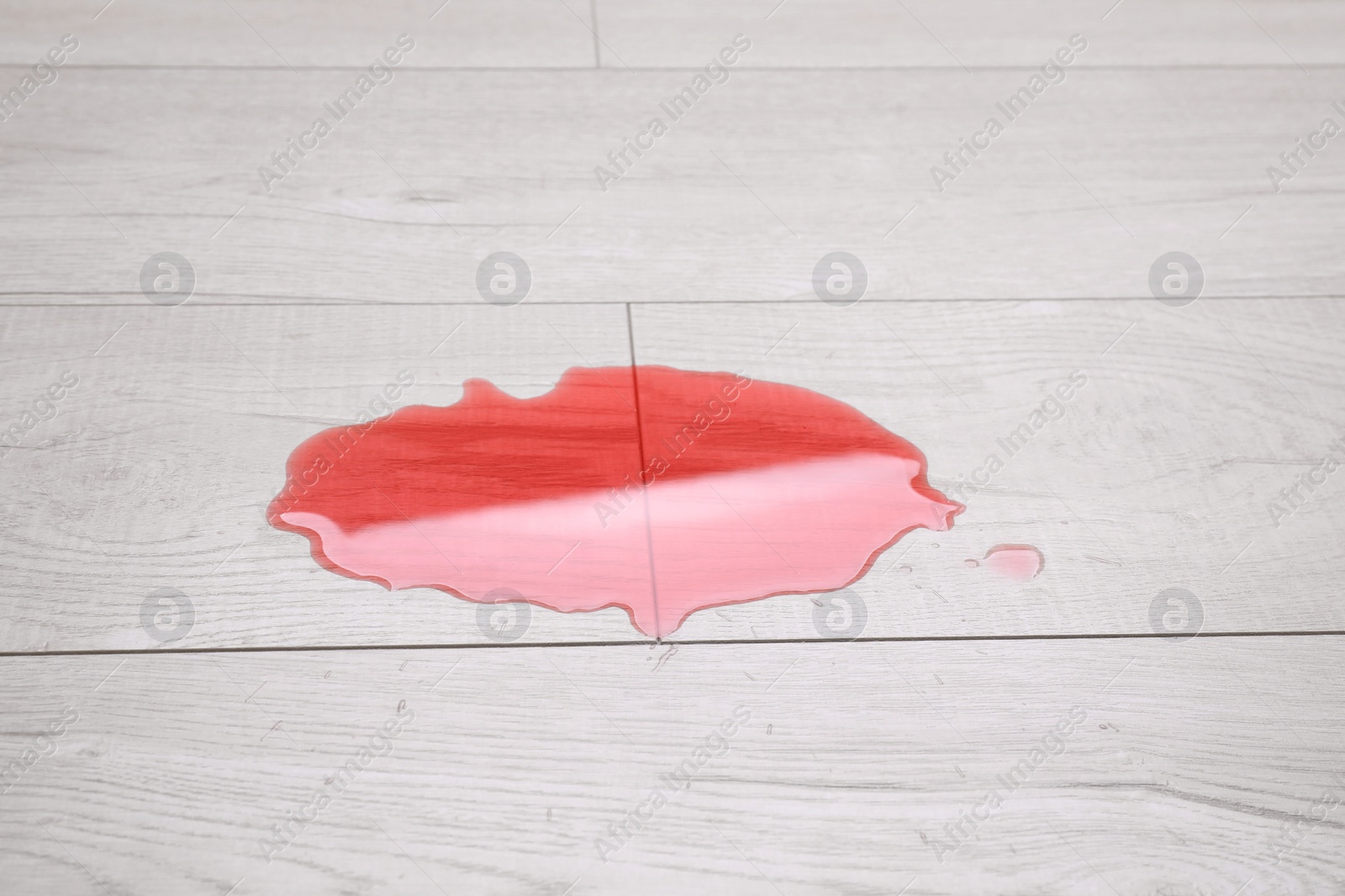 Photo of Puddle of red liquid on wooden floor