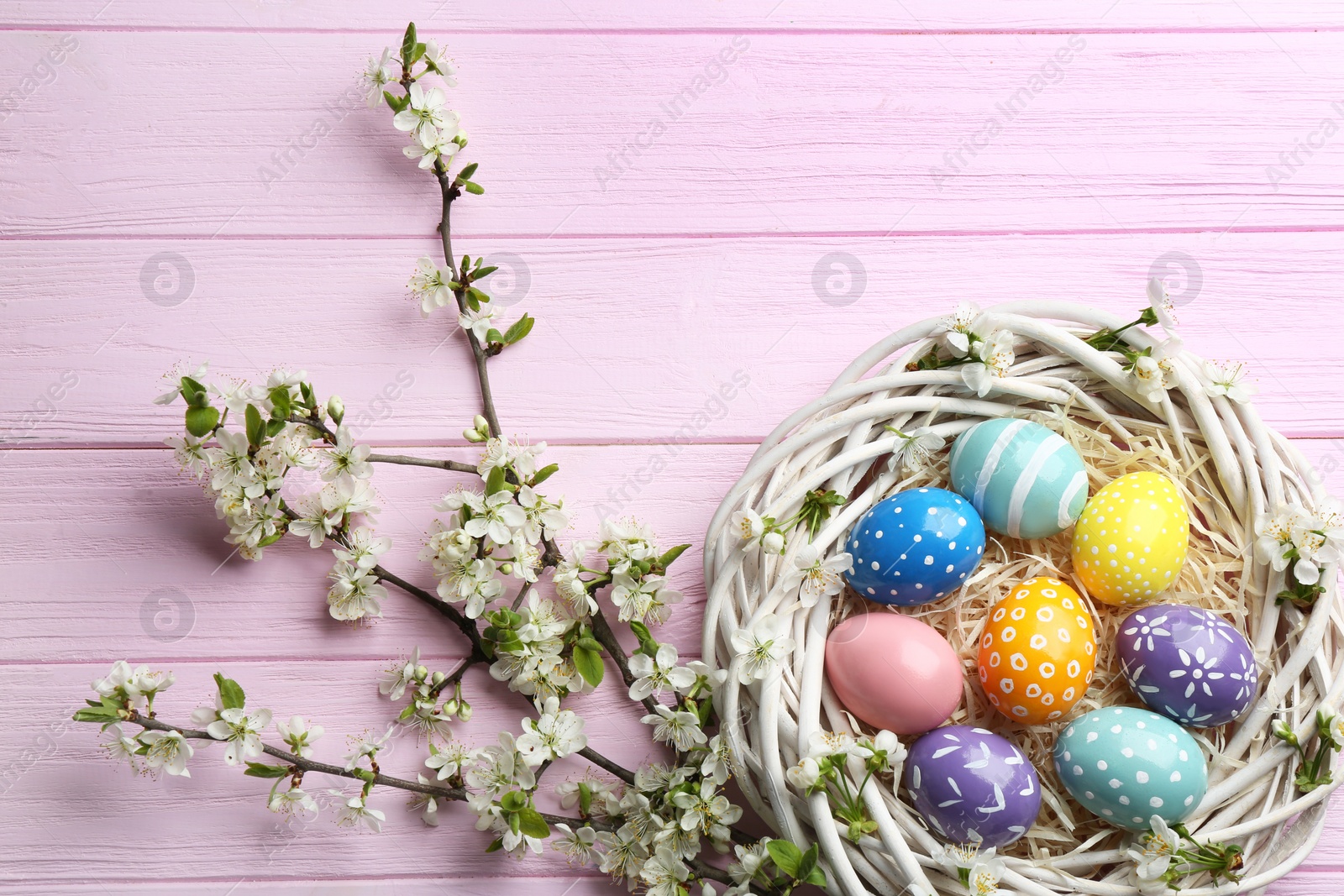 Photo of Flat lay composition with painted Easter eggs and blossoming branches on wooden background