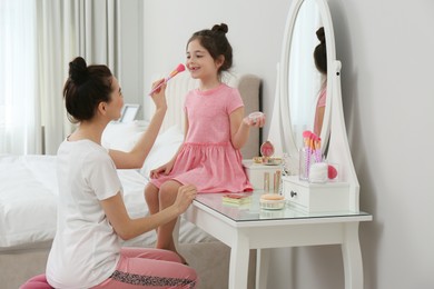 Photo of Young mother and her daughter spending time together in bedroom
