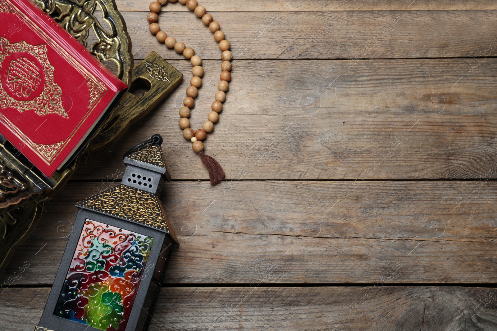 Photo of Arabic lantern, quran and misbaha on wooden table, flat lay. Space for text