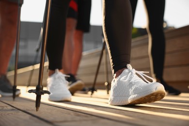 Photo of Group of people practicing Nordic walking with poles outdoors, closeup