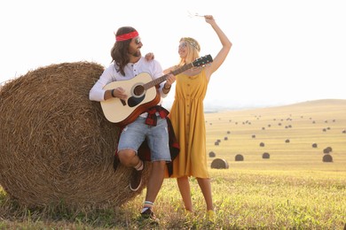 Beautiful hippie woman listening to her friend playing guitar in field, space for text