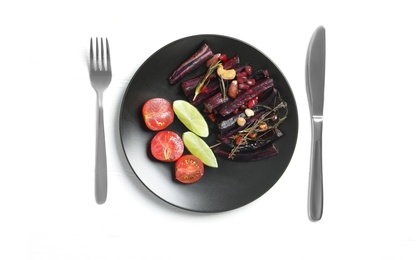 Photo of Baked black carrot served on white table, flat lay