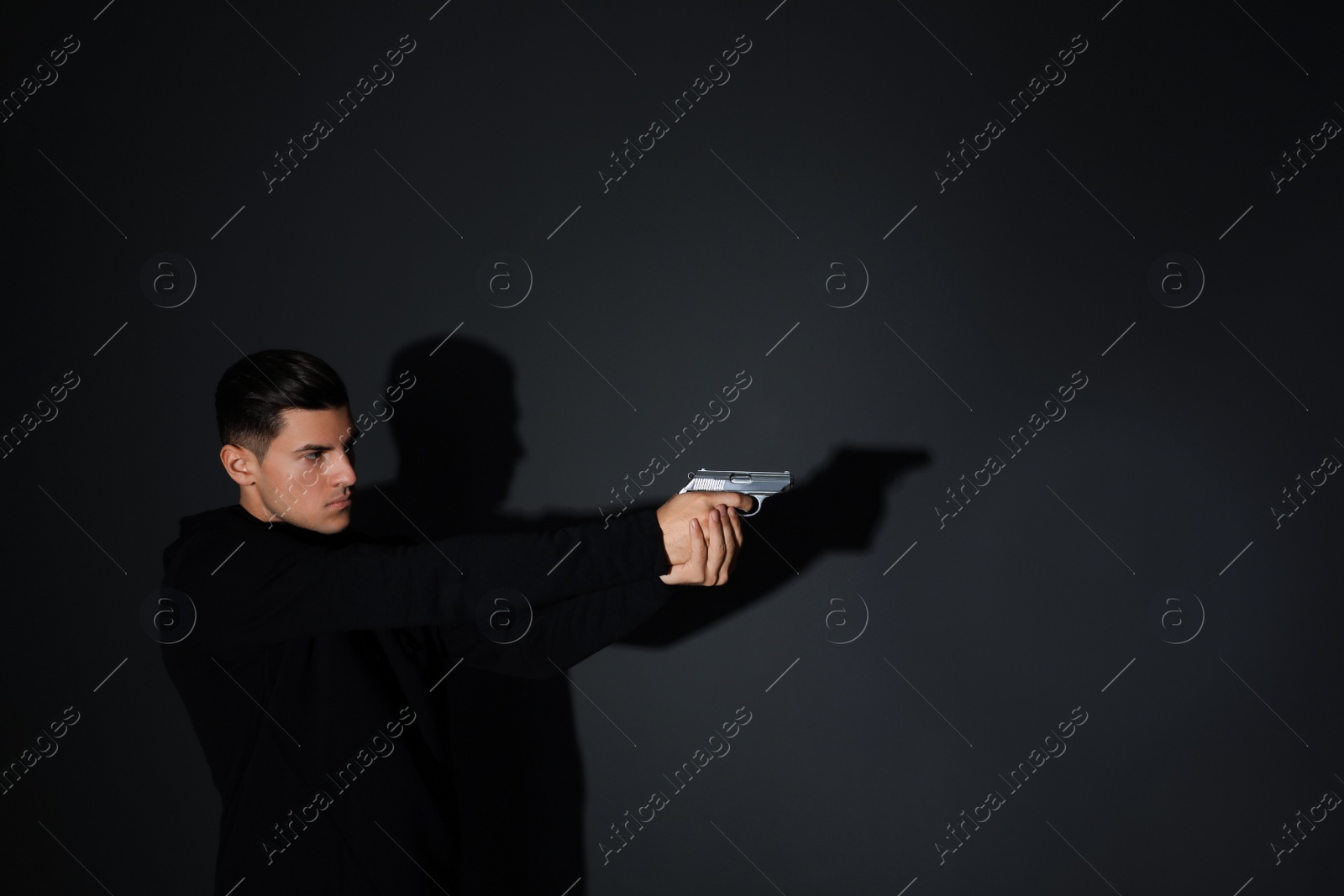 Photo of Professional killer with gun on black background