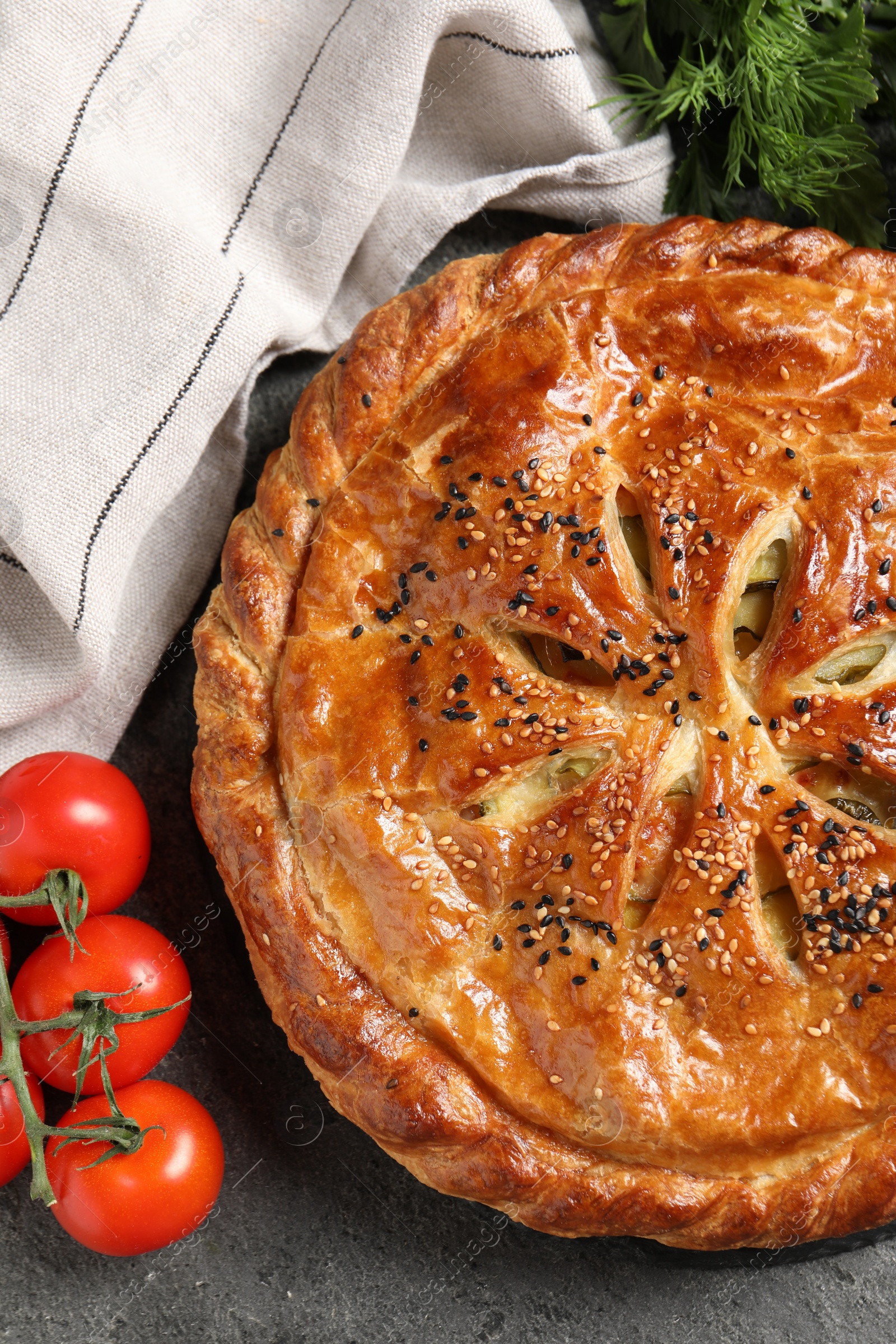 Photo of Tasty homemade pie, spices and fresh tomatoes on grey table, flat lay