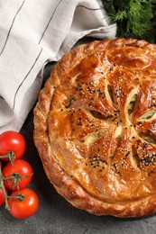 Photo of Tasty homemade pie, spices and fresh tomatoes on grey table, flat lay