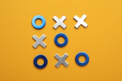 Photo of Tic tac toe set on yellow background, flat lay