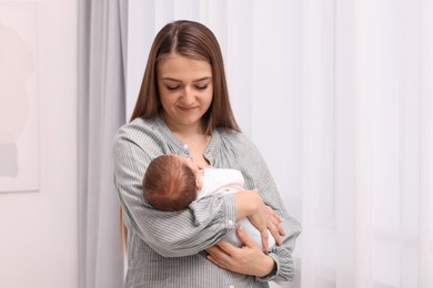 Photo of Mother with her cute newborn baby indoors. Space for text