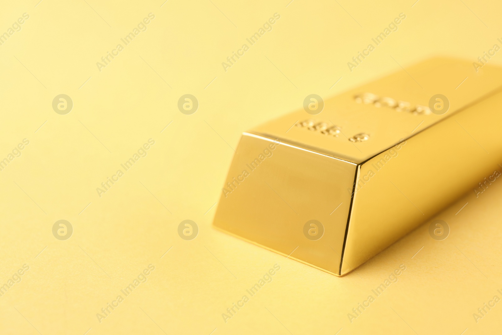 Photo of Shiny gold bar on color background, closeup. Space for text