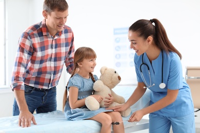 Children's doctor examining little girl near parent in hospital