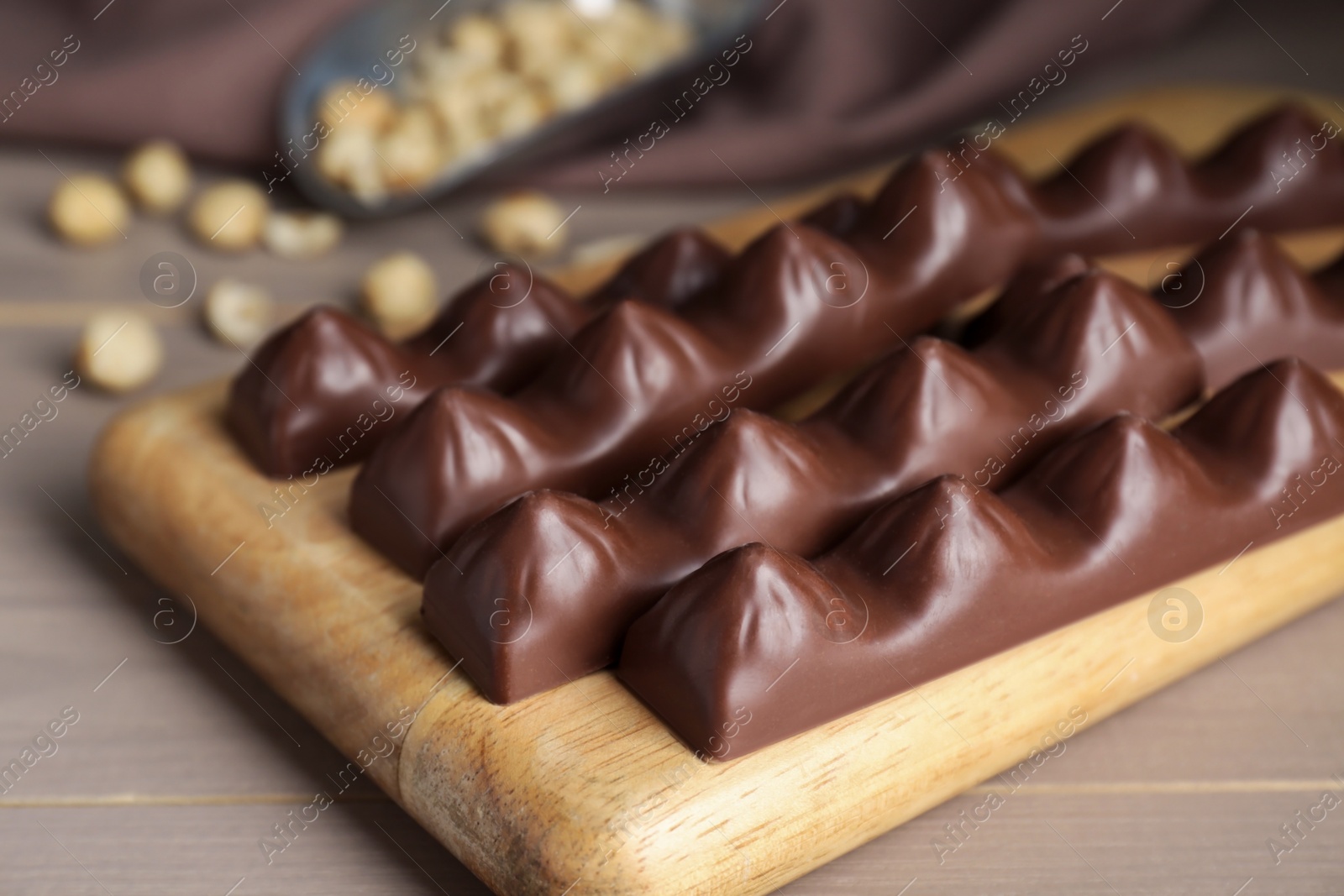 Photo of Board with tasty chocolate bars on wooden table, closeup