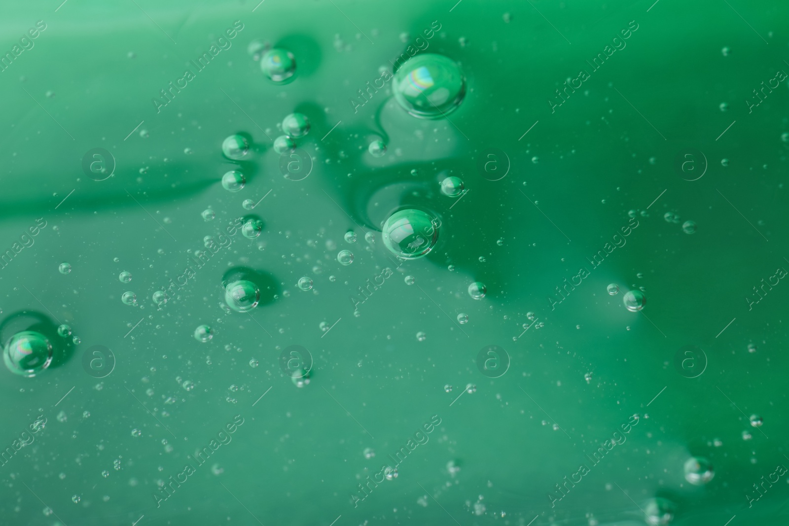 Photo of Pure transparent cosmetic gel on green background, closeup