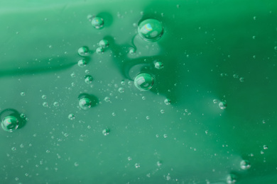 Photo of Pure transparent cosmetic gel on green background, closeup