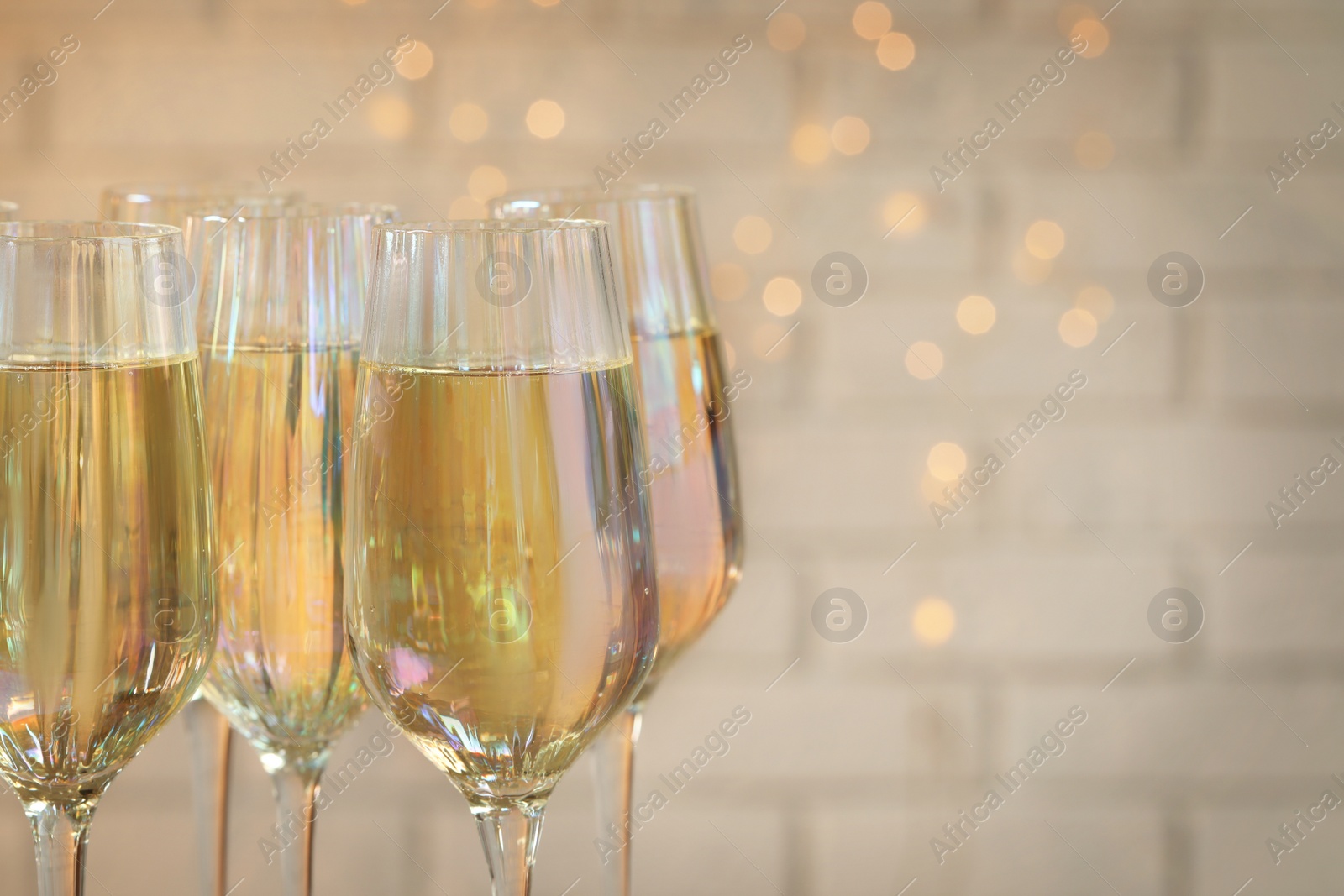 Photo of Glasses of champagne against blurred lights, closeup. Space for text