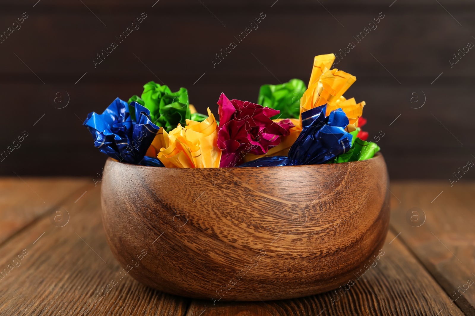 Photo of Candies in colorful wrappers on wooden table, closeup