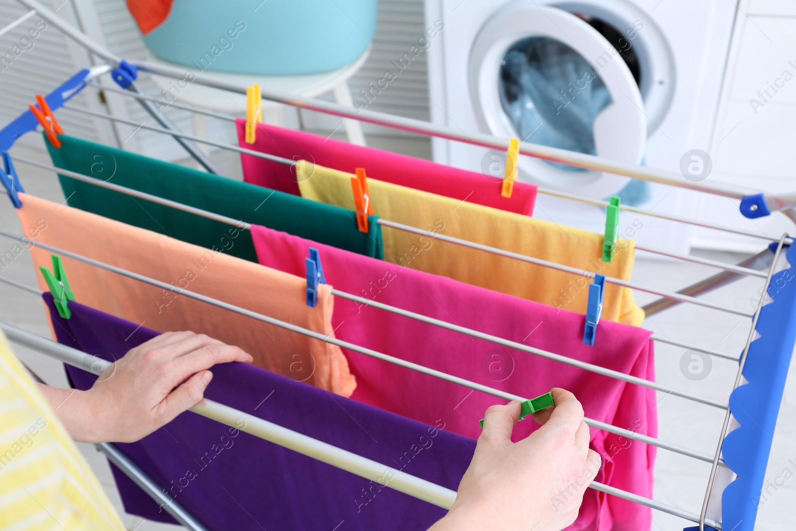 Photo of Woman hanging clean laundry on drying rack indoors, closeup