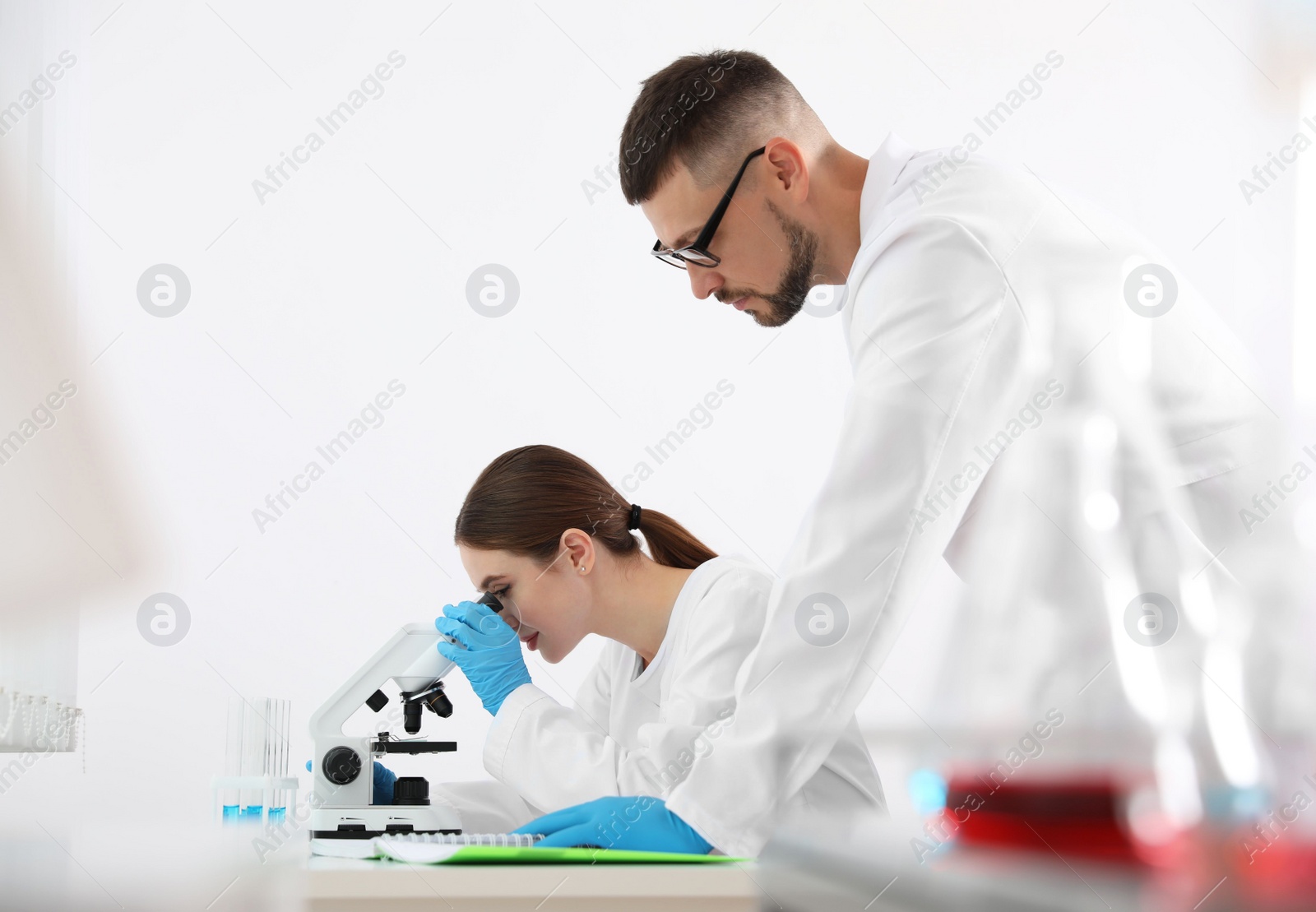 Photo of Scientist using microscope at table and colleague in laboratory. Medical research