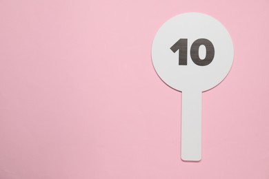 Auction paddle with number 10 on pink background, top view. Space for text