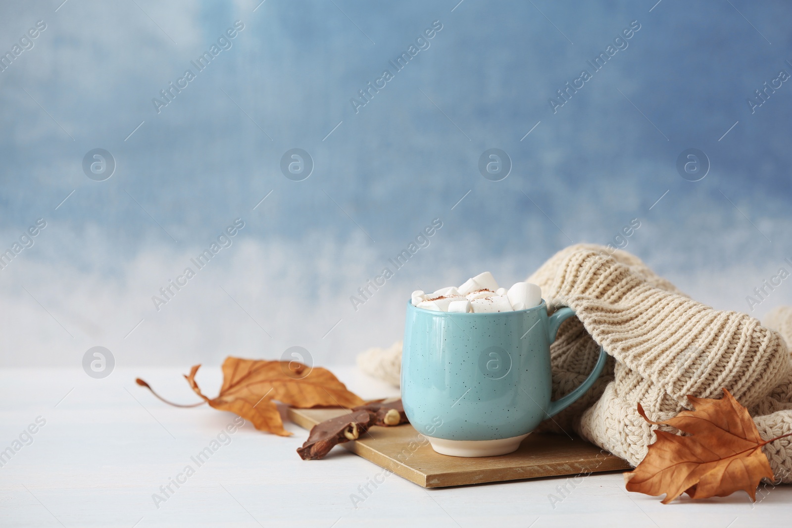 Photo of Composition with hot cozy drink in cup and autumn clothing on table