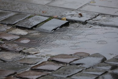 Photo of Rippled puddle on pavement on rainy day