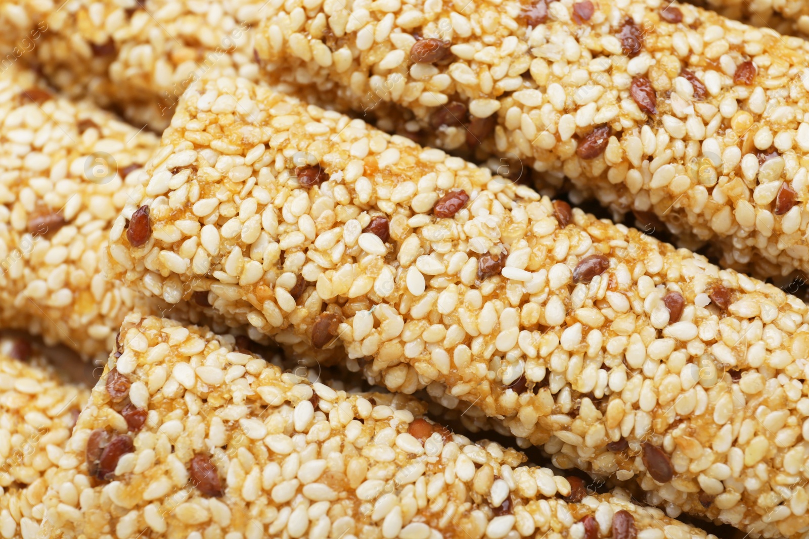 Photo of Tasty sesame seed bars as background, closeup