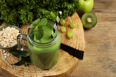 Photo of Mason jar of fresh green smoothie and ingredients on wooden table
