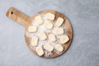 Photo of Making lazy dumplings. Board with cut dough and flour on grey table, top view