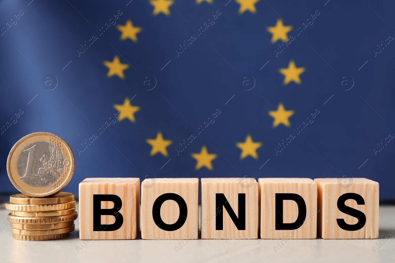Photo of Word Bonds made of wooden cubes with letters and stacked coins against European union flag