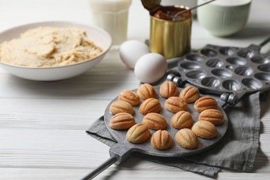 Delicious walnut shaped cookies with condensed milk and ingredients on white wooden table. Space for text