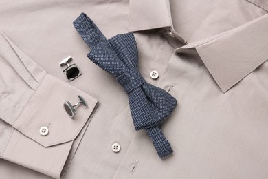 Photo of Stylish blue bow tie and cufflinks on beige shirt, top view