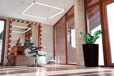 Photo of Stylish hairdresser's workplace with professional armchair and large mirror in barbershop, low angle view. Interior design