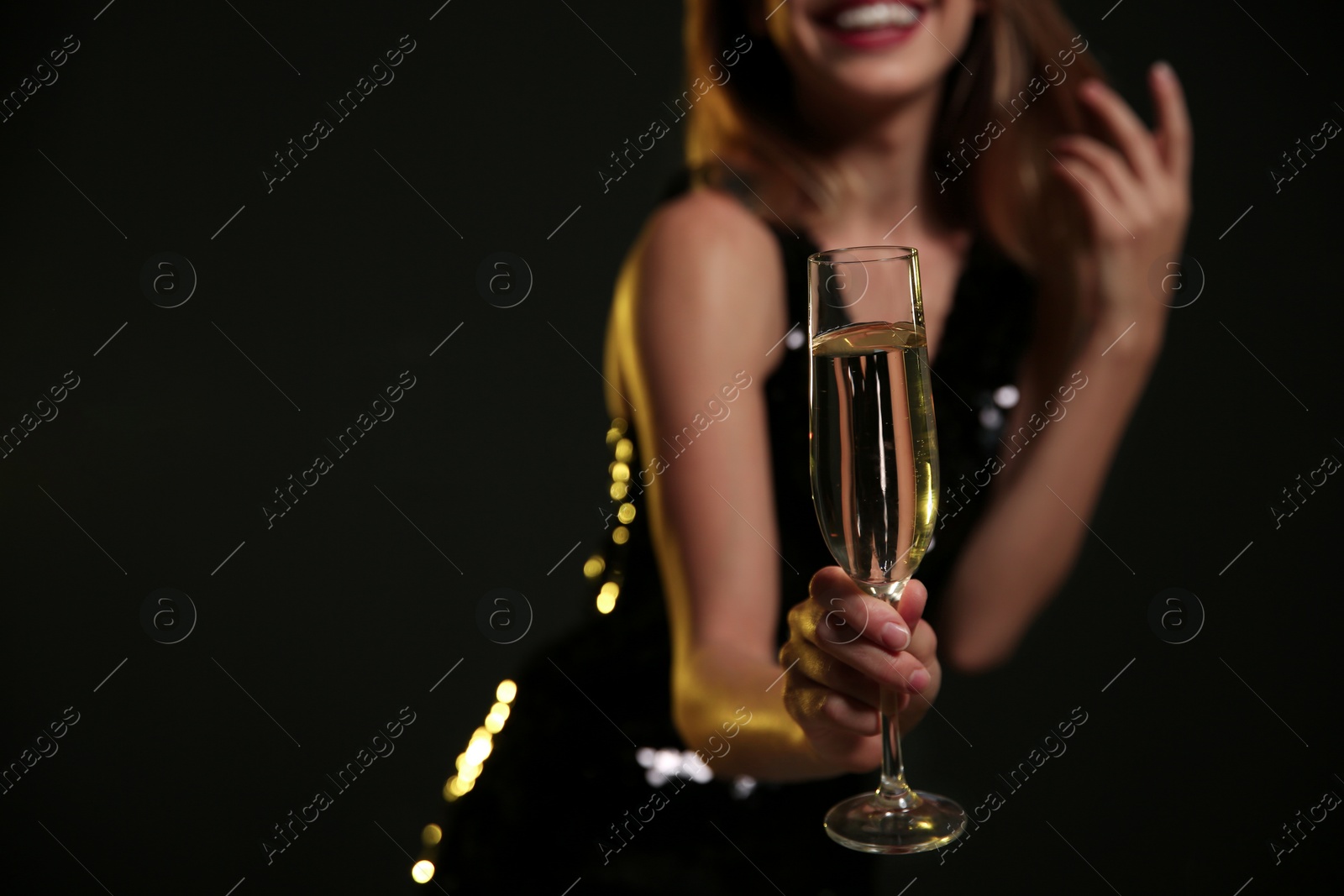 Photo of Beautiful woman with glass of champagne on dark background, closeup. Space for text