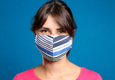 Young woman in protective face mask on blue background