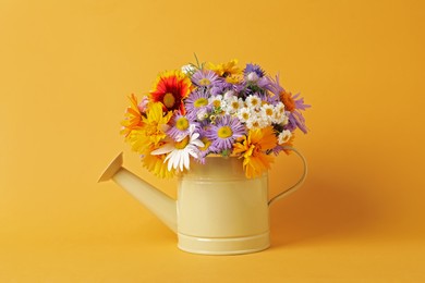 Photo of Watering can with beautiful flowers on yellow background