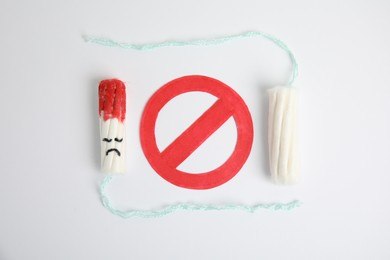 Photo of Clean and used tampons with sign Stop on light background, flat lay