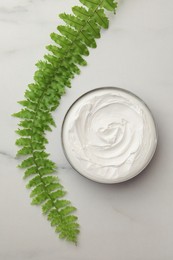 Photo of Jar of face cream and green plant on white marble table, flat lay